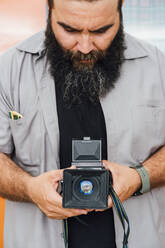 Bearded man taking photo with camera - JCMF00563