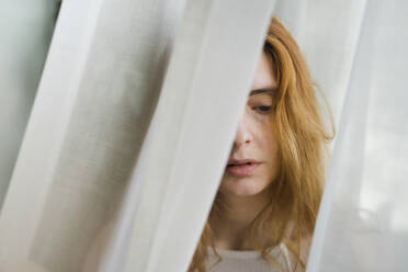 Porträt einer traurigen jungen Frau in einem Vorhang - AFVF05956