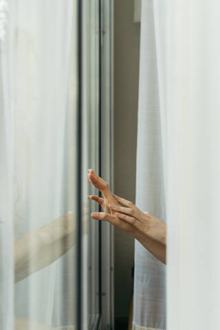 Hand einer Frau berührt Fensterscheibe, lizenzfreies Stockfoto