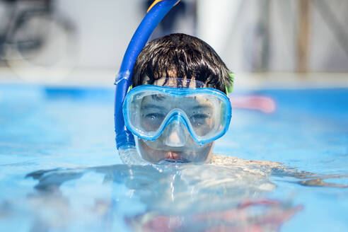 Porträt eines Jungen mit Taucherbrille im Schwimmbad - OCMF01170