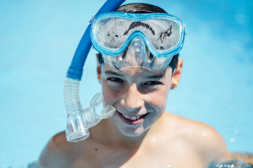 Porträt eines lächelnden Jungen mit Taucherbrille im Schwimmbad - OCMF01171