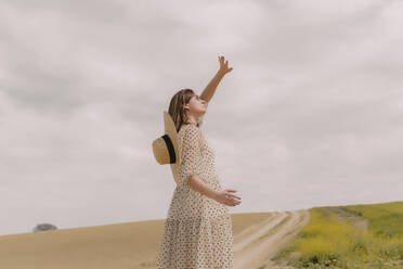 Woman in vintage dress alone at a remote field in the countryside - ERRF03071