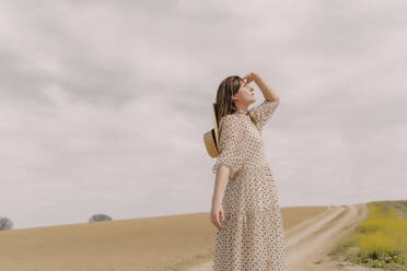 Frau in Vintage-Kleid allein auf einem abgelegenen Feld auf dem Lande - ERRF03072