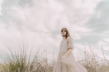 Portrait of woman in vintage dress alone at a remote field in the countryside - ERRF03110