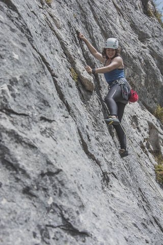 Female mountain climber climbing rock face stock photo