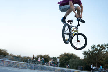 Low Section Of Man With Bicycle Performing Stunt Against Clear Sky - EYF02418
