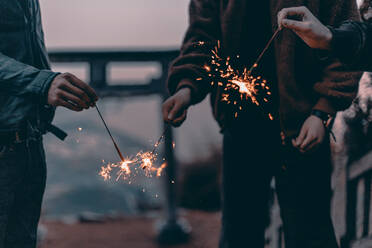 Midsection Of People Holding Sparklers At Night - EYF02452
