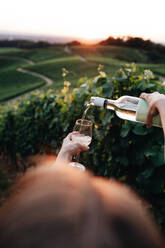 Frau gießt Wein in Glas gegen Landschaft - EYF02511