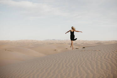 Rückenansicht einer blonden Frau, die in die Luft springt, Algodones Dunes, Brawley, USA - LHPF01215