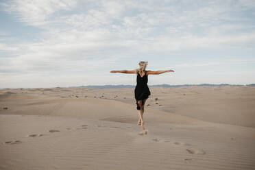 Rückenansicht einer blonden Frau, die in die Luft springt, Algodones Dunes, Brawley, USA - LHPF01219