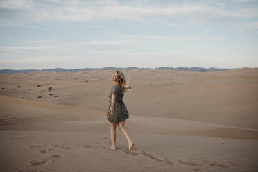 Rückenansicht einer blonden Frau, die auf einer Sanddüne läuft, Algodones Dunes, Brawley, USA - LHPF01220