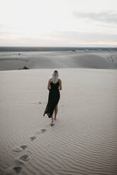 Rückenansicht einer blonden Frau, die auf einer Sanddüne läuft, Algodones Dunes, Brawley, USA - LHPF01225
