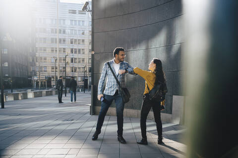 Mann und Frau grüßen mit Ellenbogen, lizenzfreies Stockfoto