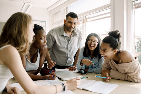 Fröhliche weibliche Teenager lernen, während der Professor am Tisch im Klassenzimmer steht - MASF17373