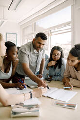 Professor unterrichtet weibliche Teenager, während er am Tisch im Klassenzimmer steht - MASF17375