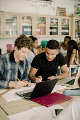 Männliche Studenten studieren, während ihre Freundinnen im Hintergrund sitzen - MASF17381