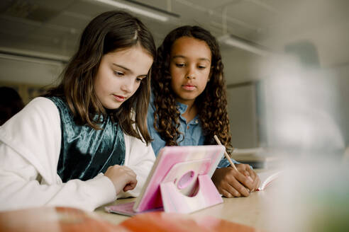 Weibliche Schüler benutzen ein digitales Tablet am Tisch im Klassenzimmer - MASF17416