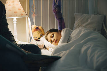 Ausgeschnittenes Bild eines Vaters, der seiner Tochter, die zu Hause im Bett schläft, ein Buch vorliest - MASF17474