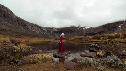 Woman Standing On Rock Amidst Mountains Against Sky - EYF02583