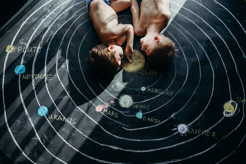 High Angle View Of Shirtless Siblings Lying On Chalk Drawing - EYF02603