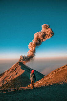 Rückansicht einer Frau, die in der Nähe eines aktiven Vulkans steht - EYF02640