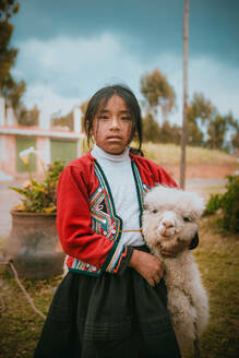 Porträt von Teenager-Mädchen stehend mit Alpaka auf Feld - EYF02680