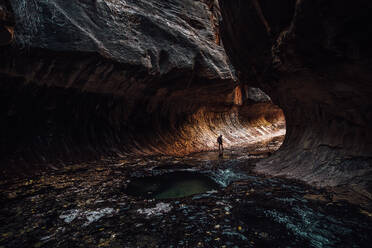 Silhouette Frau geht durch Felsformation in Höhle - EYF02762