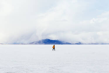 Distance Shot von Frau zu Fuß auf Schnee bedeckte Landschaft - EYF02775