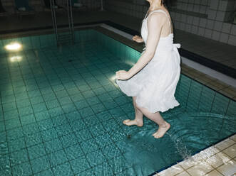Niedriger Ausschnitt einer Frau, die nachts ins Schwimmbad springt - EYF02799