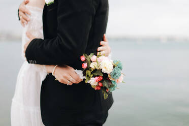 Midsection Of Newlywed Couple Embracing While Standing By Sea Against Sky - EYF02887