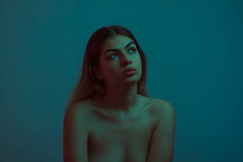 Nachdenkliche junge Frau vor blauem Hintergrund - EYF02952