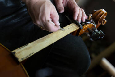 Abgeschnittene Hände einer Frau, die eine Violine repariert - EYF03030