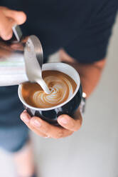 Mittelteil eines Mannes bei der Zubereitung von Kaffee in einem Cafe - EYF03053