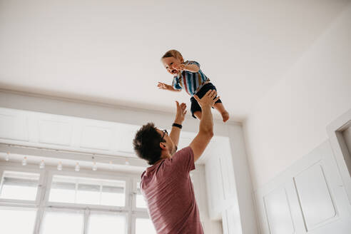 Low Angle View of Playful Vater Catching Sohn zu Hause - EYF03097