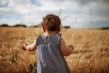 Rückansicht des niedlichen Babys, das auf dem Land gegen den Himmel steht - EYF03218