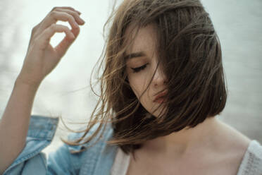 Close-Up Of Young Woman With Tousled Hair Against Lake - EYF03226