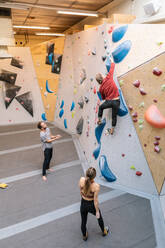 Hohe Winkel Ansicht der männlichen und weiblichen Studenten Blick auf reifen Trainer Kletterwand in der Turnhalle - MASF17527