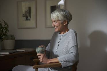 Ältere Frau entspannt sich mit einer Tasse Tee zu Hause - AUF00301