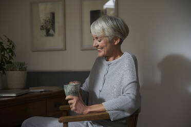 Senior woman relaxing with cup of tea at home - AUF00301