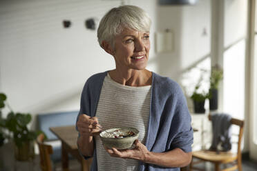 Portrait of senior woman holding bowl of granola with yoghurt and berries - AUF00314