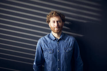 Portrait of a casual businessman standing at a wall - RBF07242