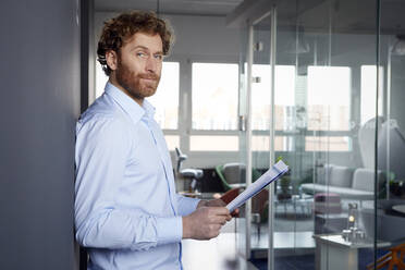 Portrait of a businessman with papers in office - RBF07262