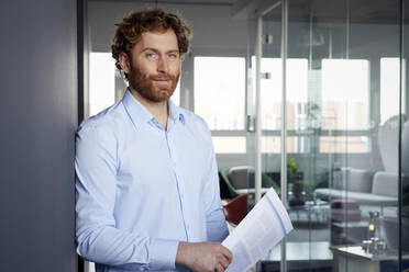 Portrait of a businessman with papers in office - RBF07263