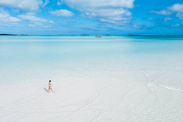 Woman walking on white sand bank in the sea, Bahamas, Carribean - DAWF01311