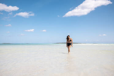 Woman walking on white sand bank in the sea, Bahamas, Carribean - DAWF01325