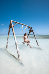 Frau schwingt auf einer Schaukel im Meer, Bahamas, Karibik - DAWF01327