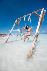 Frau schwingt auf einer Schaukel im Meer, Bahamas, Karibik - DAWF01329