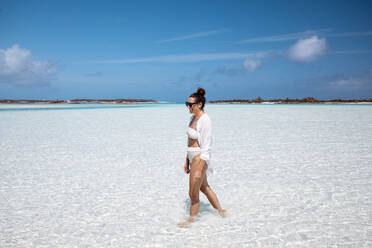 Woman walking on white sand bank in the sea, Bahamas, Carribean - DAWF01344