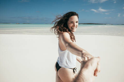 Frau hält Hand von Mann und spaziert am Strand, lizenzfreies Stockfoto