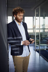 Geschäftsmann benutzt Mobiltelefon im Büro - RBF07301